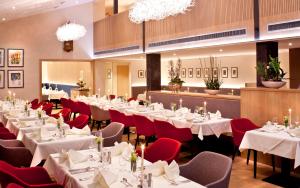 ein Restaurant mit weißen Tischen und roten Stühlen in der Unterkunft Hotel Hofmark in Bad Birnbach