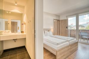a bedroom with a bed and a sink and a mirror at COOEE alpin Hotel Kitzbüheler Alpen in Sankt Johann in Tirol