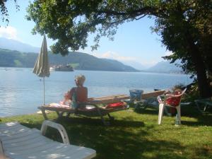 a woman sitting on a bench next to a lake at Seefels Appartements in Döbriach