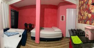 two beds in a room with pink walls at Hospedagem Mariano in Arraial do Cabo