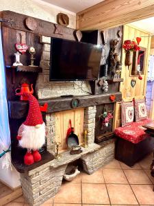 Ein Zimmer mit Fernseher und Kamin mit einer Weihnachtsmannfigur in der Unterkunft Le Grenier de Olga e Mario in Pré-Saint-Didier