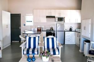 a kitchen with white cabinets and blue and white chairs at 27 On Ray in Britannia Bay