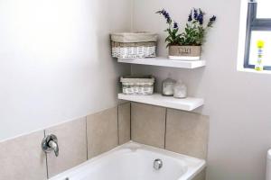 a bathroom with a sink and shelves with flowers at 27 On Ray in Britannia Bay +45 photos