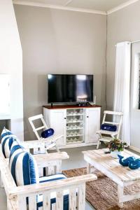 a living room with a tv and a couch and chairs at 27 On Ray in Britannia Bay