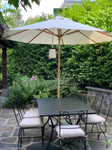 a table and chairs with an umbrella on a patio at 'Le Petit Clos Suites'- Charming Getaway on Leman Lake in Nyon