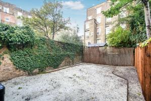 a backyard with a fence next to a brick wall at Portobello 2-Bed Apartment in London