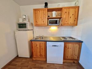 Una pequeña cocina con fregadero y refrigerador. en Appartement Modane 4 pièces, idéal ski, 6-8 pers, 65m², proche télécabine et commerces - FR-1-265-66, en Valfréjus