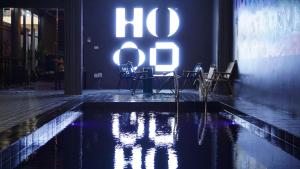 a swimming pool with chairs and a lit up sign at Hood hostel in Jomtien Beach