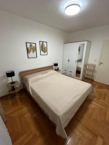 een slaapkamer met een groot bed en houten vloeren bij Apartmani Adele in Srima