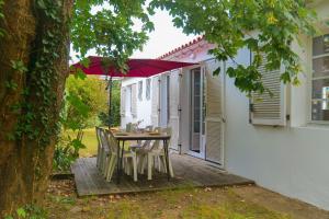 a patio with a table and chairs under an umbrella at maison au calme la chaume 6 personnes in La Chaume