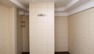 a bathroom with a shower with white tiled walls at Hostel Old Town in Bratislava