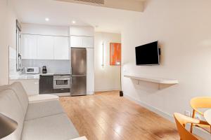 a living room with a couch and a kitchen at B&B HOTEL Apartamentos Madrid Centro Fuencarral 46 in Madrid