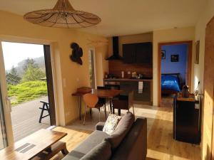 uma sala de estar com um sofá e uma mesa e uma cozinha em La chouette dort le gîte du retour à la source em Dabo