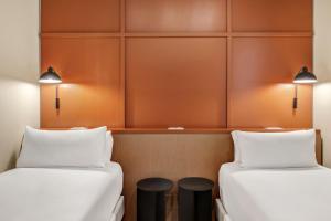 two beds in a room with orange walls at B&B HOTEL Apartamentos Madrid Centro Fuencarral 46 in Madrid