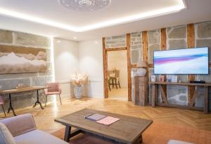 a living room with a tv and a stone wall at Exklusive Stadtwohnung mit Innenhofterrasse, Pool und Sauna in Bern