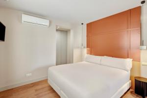a bedroom with a white bed and a wooden headboard at B&B HOTEL Apartamentos Madrid Centro Fuencarral 46 in Madrid