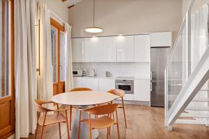 a white kitchen with a table and chairs at B&B HOTEL Apartamentos Madrid Centro Fuencarral 46 in Madrid