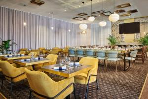 ein Restaurant mit Tischen und Stühlen und einem Flachbildfernseher in der Unterkunft Hotel Gatsby by HappyCulture in Chassieu