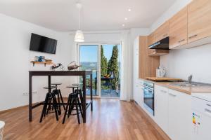 a kitchen with white cabinets and a table with stools at Apartments Lotus in Trogir