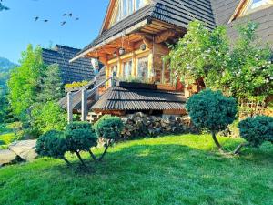 a large wooden house with trees in front of it at GORSKA OSADA Lovely Chalets Zakopane in Poronin