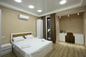 a bedroom with a white bed and a desk and a kitchen at Chanko Hotel in Borjomi