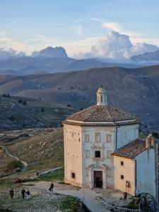 a building on a hill with people standing around it at Casa Adelina by TraMonti Apartments in Poggio Picenze