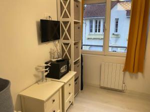 a room with a shelf with a television and a window at La clairière Merlimont in Merlimont