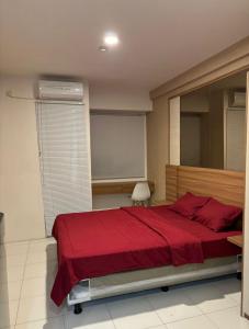 a bedroom with a large bed with a red blanket at Apartemen Riverview Tower Mahakam With Netflix By UVroomsOfficial in Tegalgede