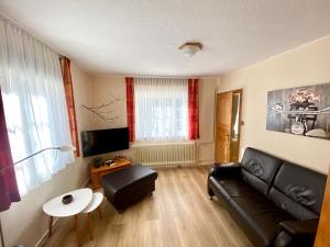 a living room with a black leather couch and a table at Ferienwohnung GARTENBLICK im HAUS GERLACH in Walkenried