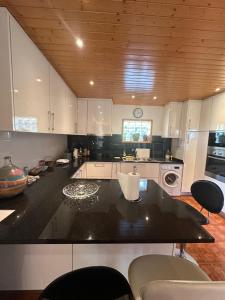 a kitchen with white cabinets and a black counter top at Casa do Vale - Seixas in Caminha +28 photos