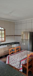 a kitchen with a table and two chairs and a refrigerator at Chácara Recanto das Pedras in Guarulhos