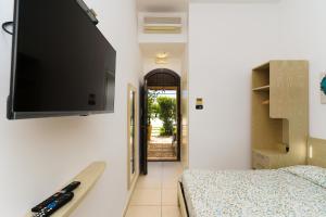a bedroom with a bed and a flat screen tv on the wall at Delle Rose, Hotel & Horse Riding in Torre Vado