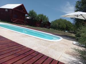 a swimming pool with an umbrella next to a house at Cabañas Lo Jhonito in Gualeguay