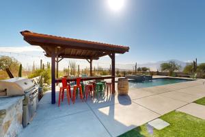 Un patio con mesa y sillas y una piscina. en Saguaro Gardens Desert Retreat, en Desert Hot Springs