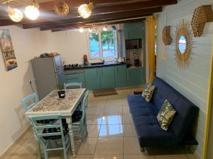 a living room with a blue couch and a table at Au coucher du soleil in Deshaies
