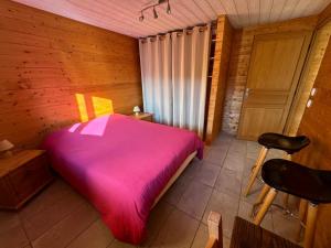 a bedroom with a pink bed in a wooden room at Les Rottes, bas ferme proche Morillon Samoens avec SPA in Verchaix