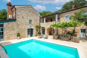 an outdoor swimming pool in front of a stone house at Villa Ivka in Tribalj