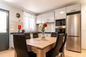 a kitchen and dining room with a wooden table and chairs at Goncalves House - AC and private parking in Calheta