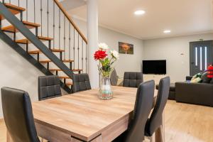 a dining room table with chairs and a vase of flowers at Goncalves House - AC and private parking in Calheta