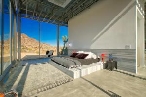 a bedroom with a bed and large glass windows at Invisible House Joshua Tree Modern Masterpiece in Joshua Tree