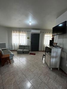 a living room with a couch and a tv at Casa ampla de 4 quartos in Piratuba