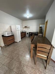 a kitchen with a wooden table and a refrigerator at Casa ampla de 4 quartos in Piratuba