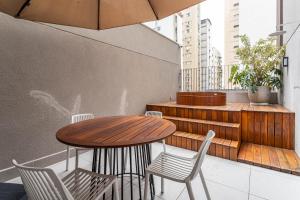 uma mesa de madeira e cadeiras numa varanda em Next Paulista by Viva - Apartamentos completos ao lado da Av Paulista e MASP em São Paulo