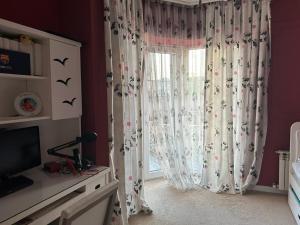 a room with a window with curtains and a television at Badamdar villa with pool and sauna in Baku