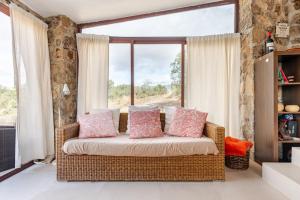 un divano in vimini in una camera con una grande finestra di Finca privada 20 hectáreas con preciosa casa de campo a Navas de San Antonio