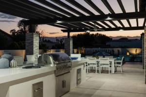 una cocina al aire libre con parrilla y mesa con sillas en Riviera - Lazy River Pool, Pickleball, Game Room!, en Bermuda Dunes