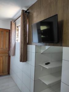 a tv on the wall of a bathroom with white tiles at Suíte e casa da vania in Ilhabela