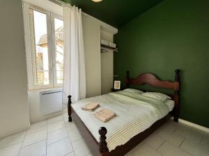 una camera da letto con un letto con una parete verde di Appartement au coeur de la ville a La Ferté-Bernard