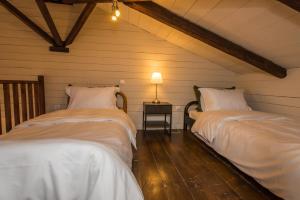 2 Betten in einem Dachzimmer mit einer Lampe auf einem Tisch in der Unterkunft Epoches Luxury Suites in Karpenisi