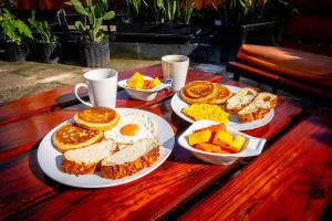 a wooden table with plates of breakfast food on it at Eden`s Garden Hostel in Panama City